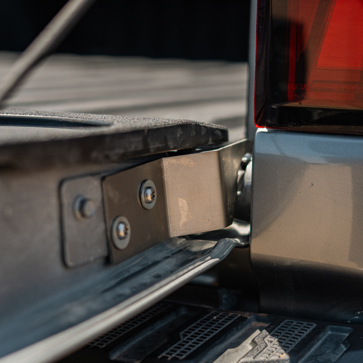 Cali Raised LED tailgate theft protector installed on a Chevy Silverado tailgate hinge, wide view showing the side step