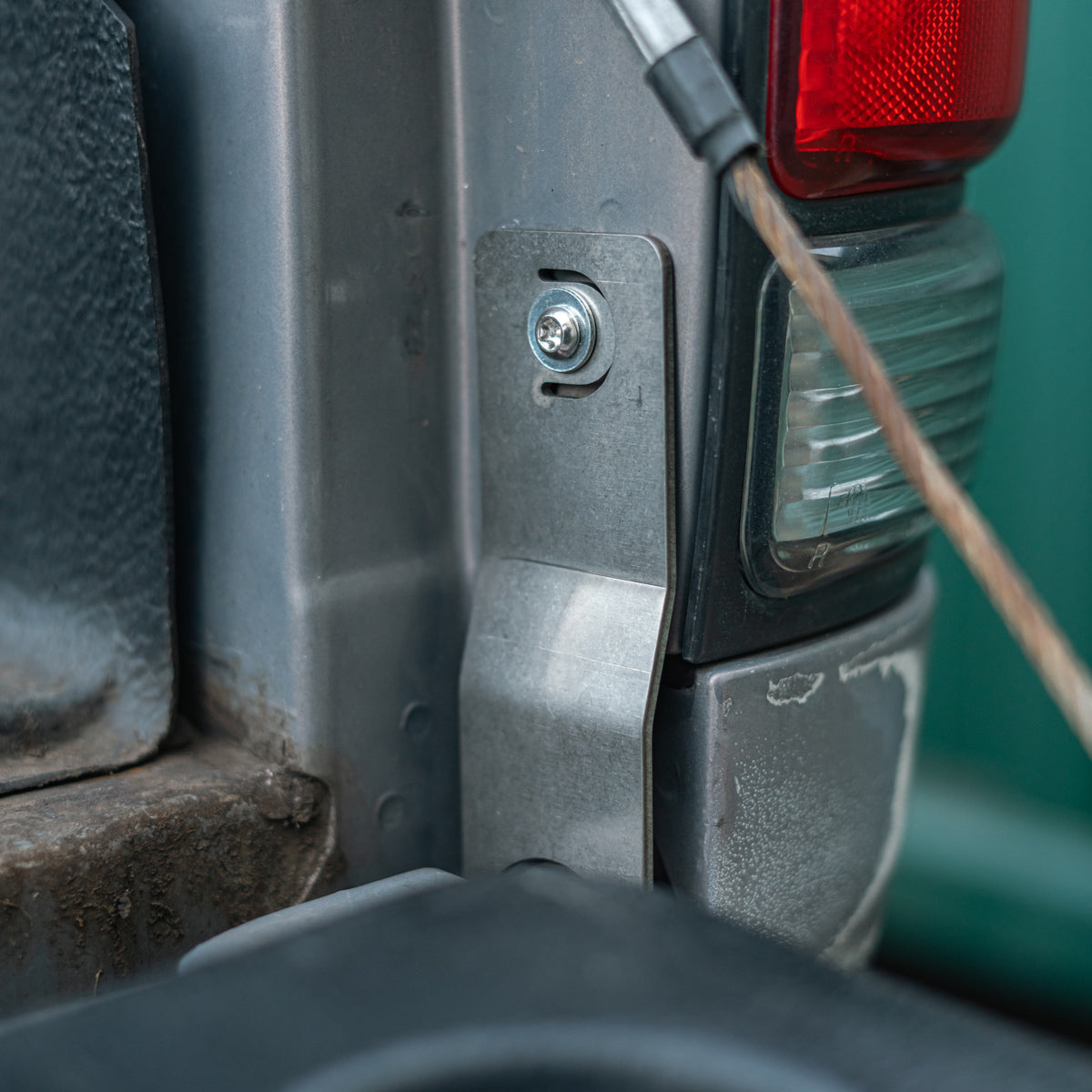 Installed tailgate theft protector next to a truck tail light with the tailgate cable visible
