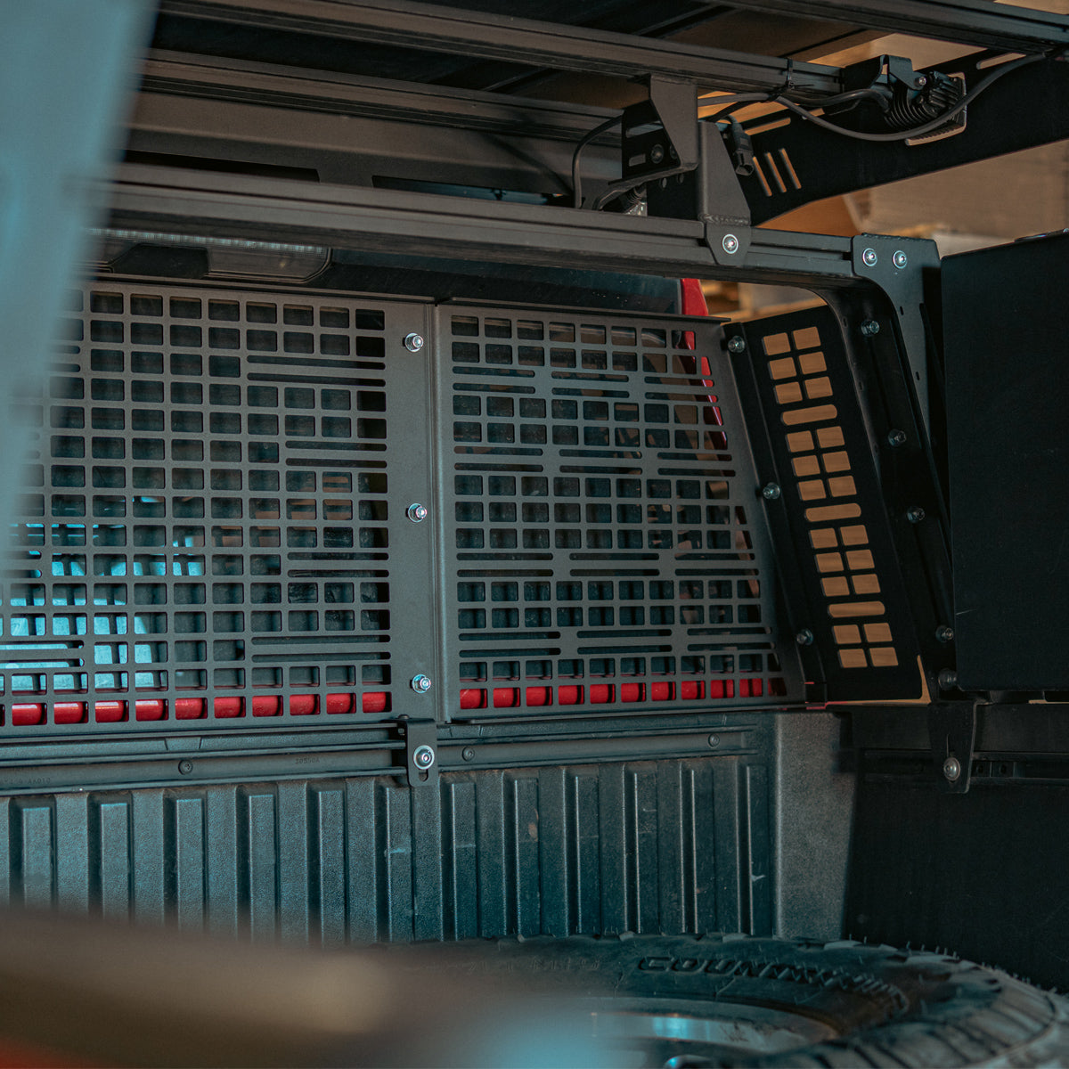 MOLLE headache rack seen from the side of a truck bed with a roof-mounted case above