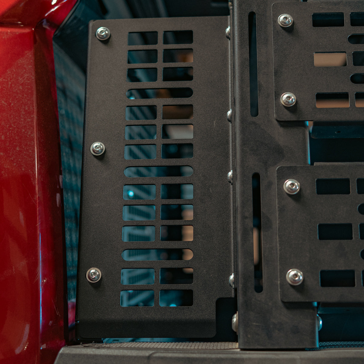 Side MOLLE panel bolted to a bed rack next to a red truck cab