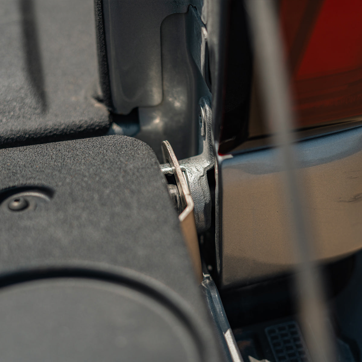 Close-up of the Cali Raised LED tailgate theft protector's security bolt on a Chevy Silverado tailgate hinge