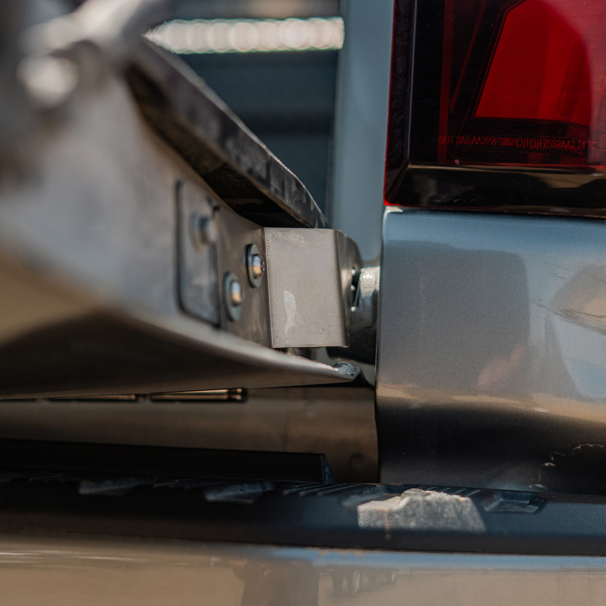 Cali Raised LED tailgate theft protector installed on a Chevy Silverado tailgate hinge, angled close-up