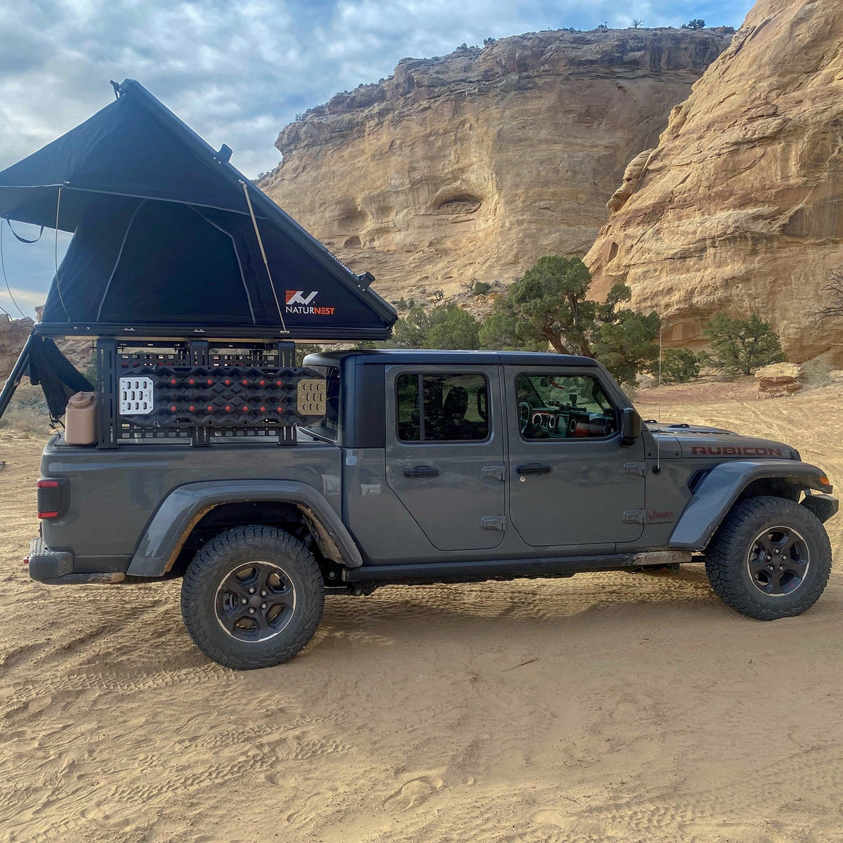 Gladiator side view with ROCK-IT rack and rooftop tent below a sandstone cliff