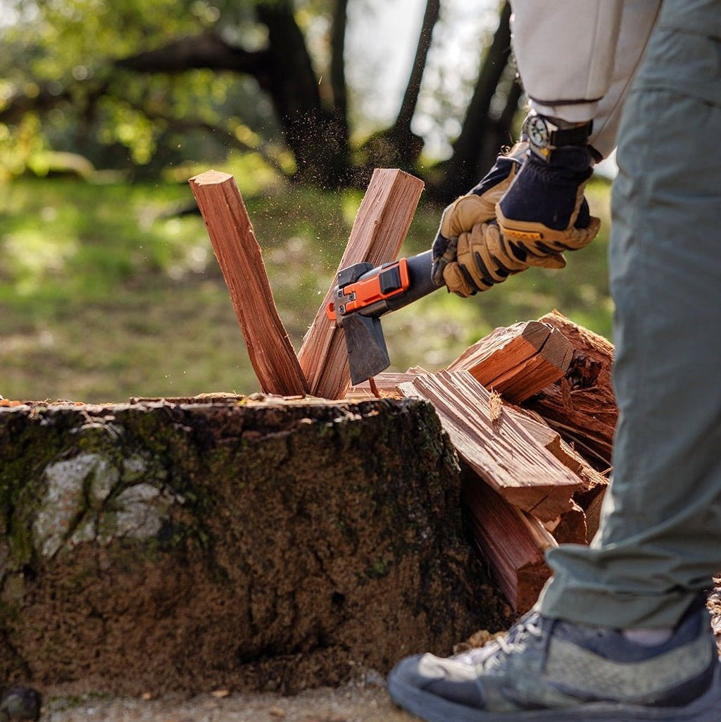 Person in work gloves splitting firewood on a stump with the Adventure Mate axe