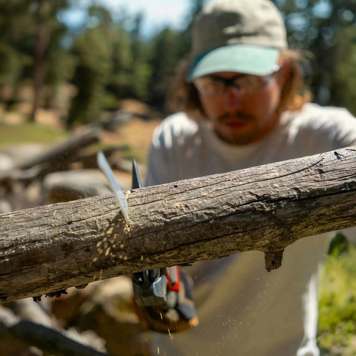 Person sawing through a log with the Adventure Mate saw