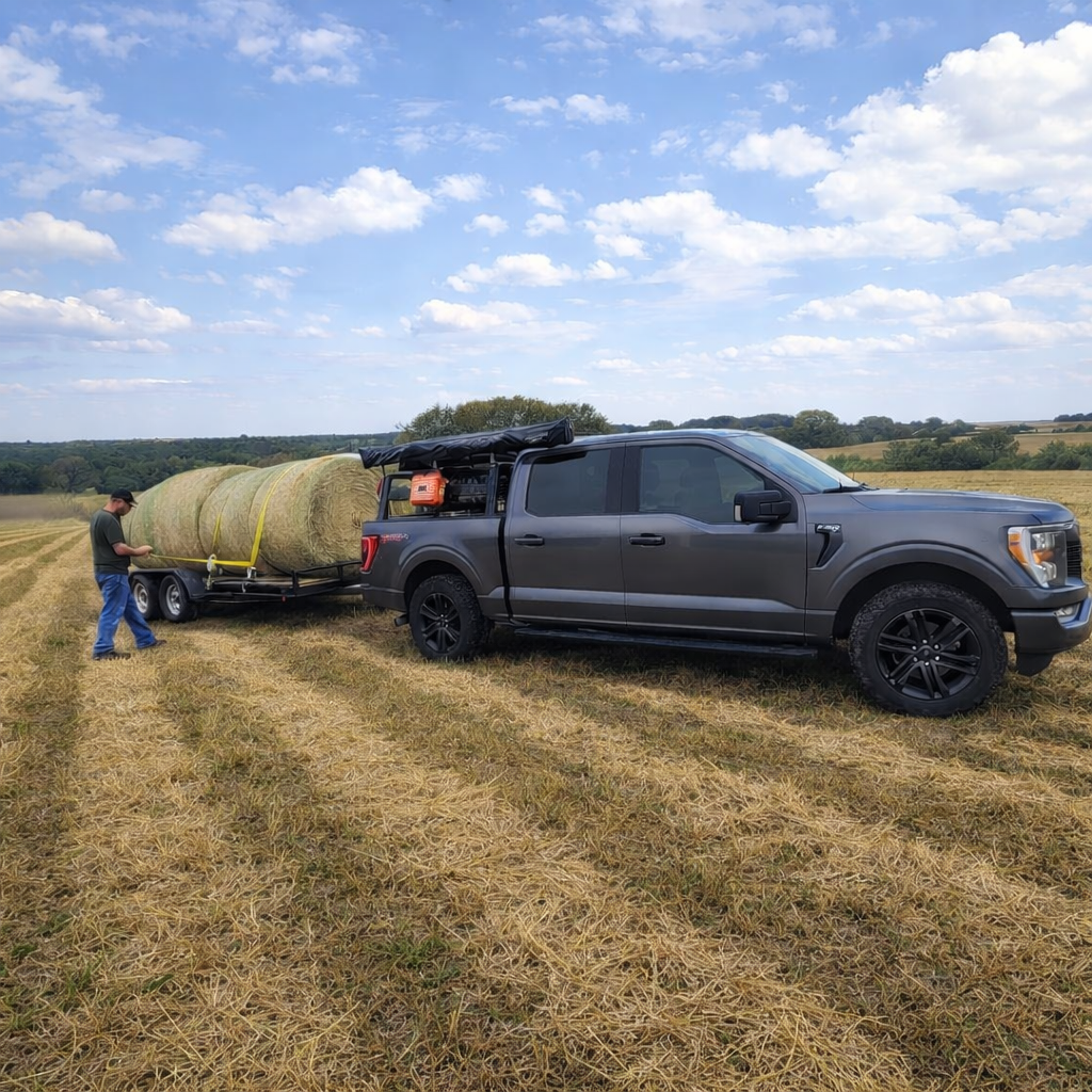 F-150 with ROCK-IT rack towing a hay trailer in a field