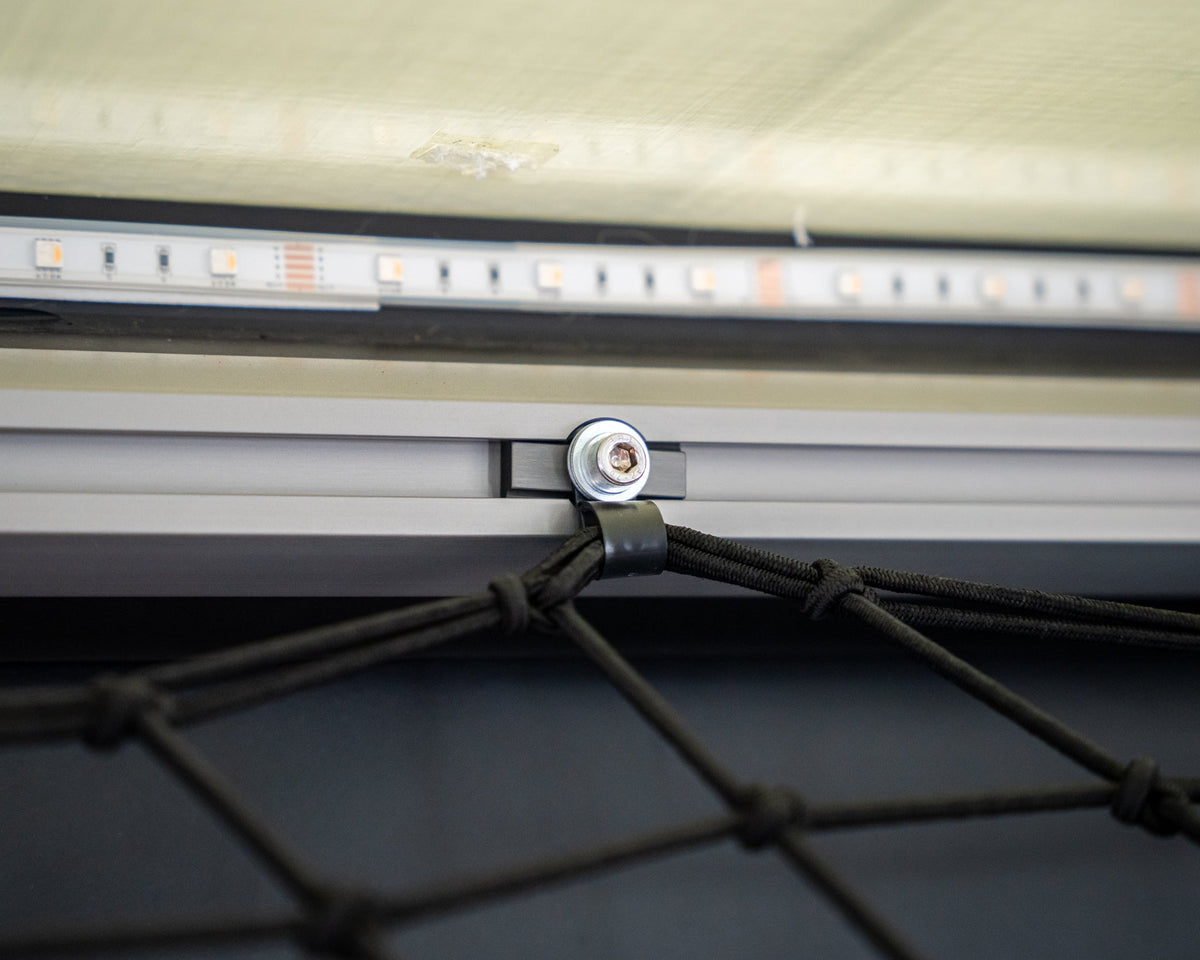 Cargo net hooked to an L-track nut bolt in a camper ceiling