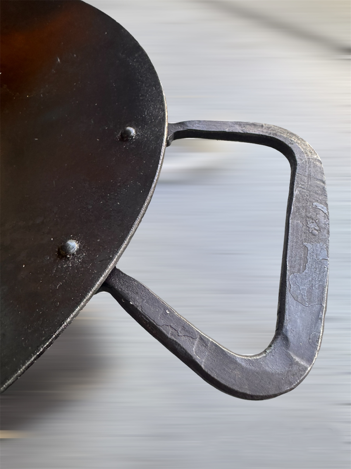 Extreme close-up, motion-blurred, of a round griddle disc's welded handle