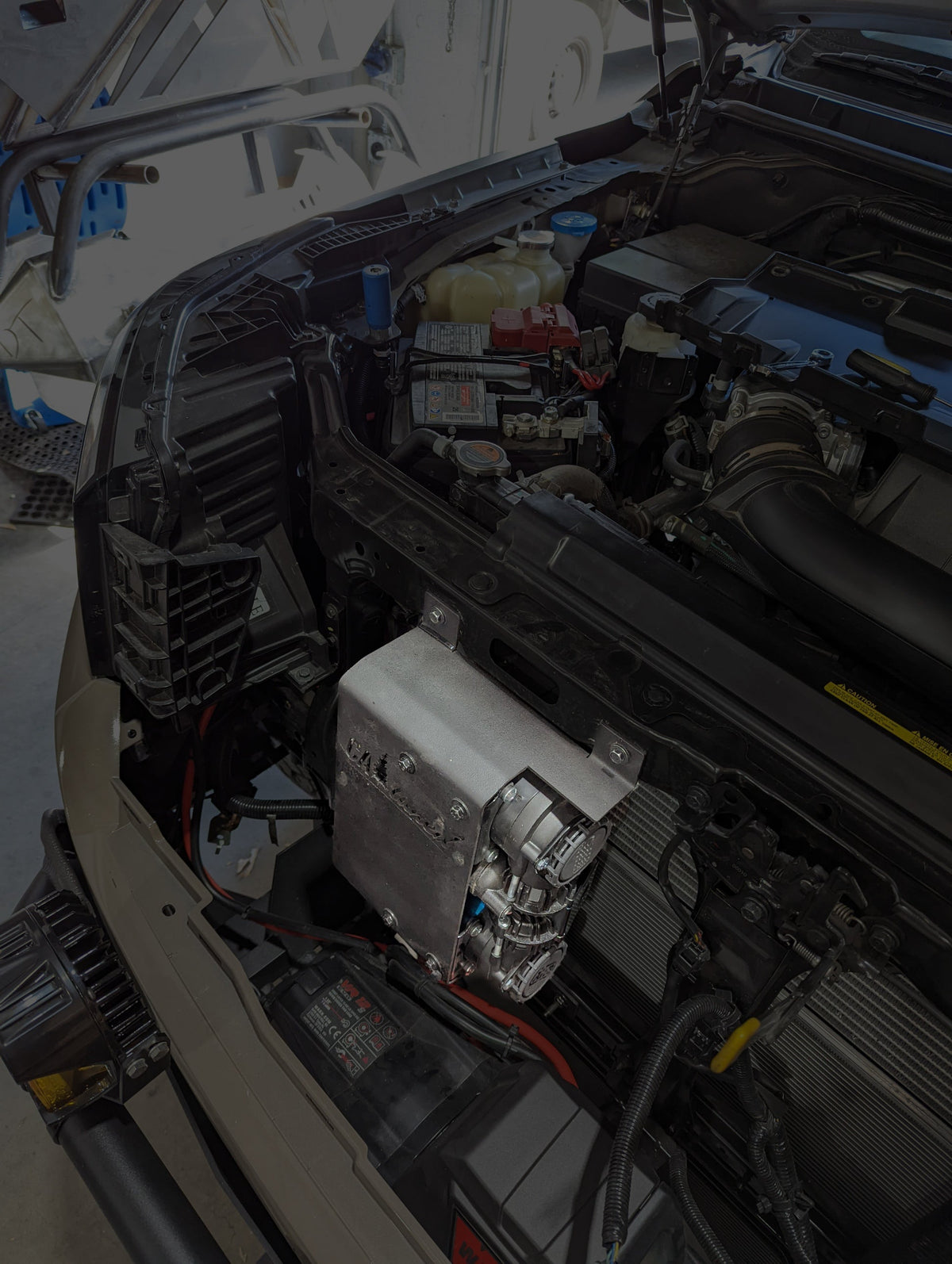 Air compressor installed on the mount in a truck engine bay
