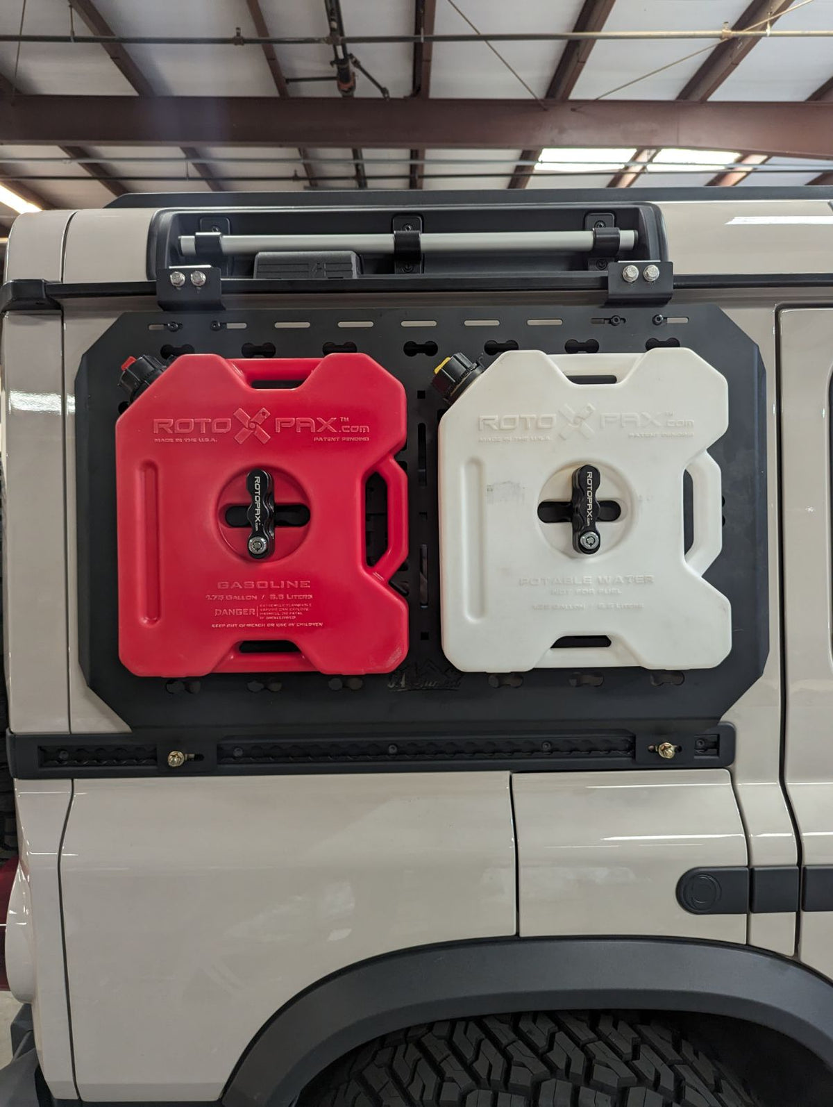 Red and white fuel cans mounted side by side on the MOLLE panel