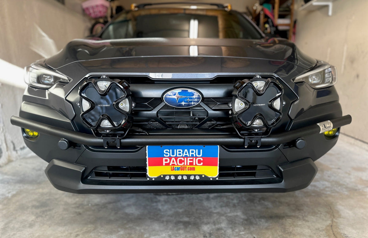 Front of a dark Subaru SUV in a garage with a brush bar and two light pods