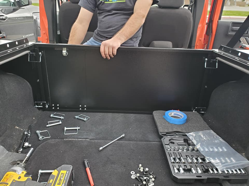 Slipstream forward wall being installed in a JKU cargo area, tools on the carpet