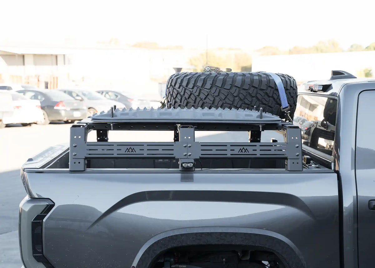 Backwoods Mid Height Toyota Tundra bed rack installed in the truck bed, with a spare tire mounted on a traction board tray