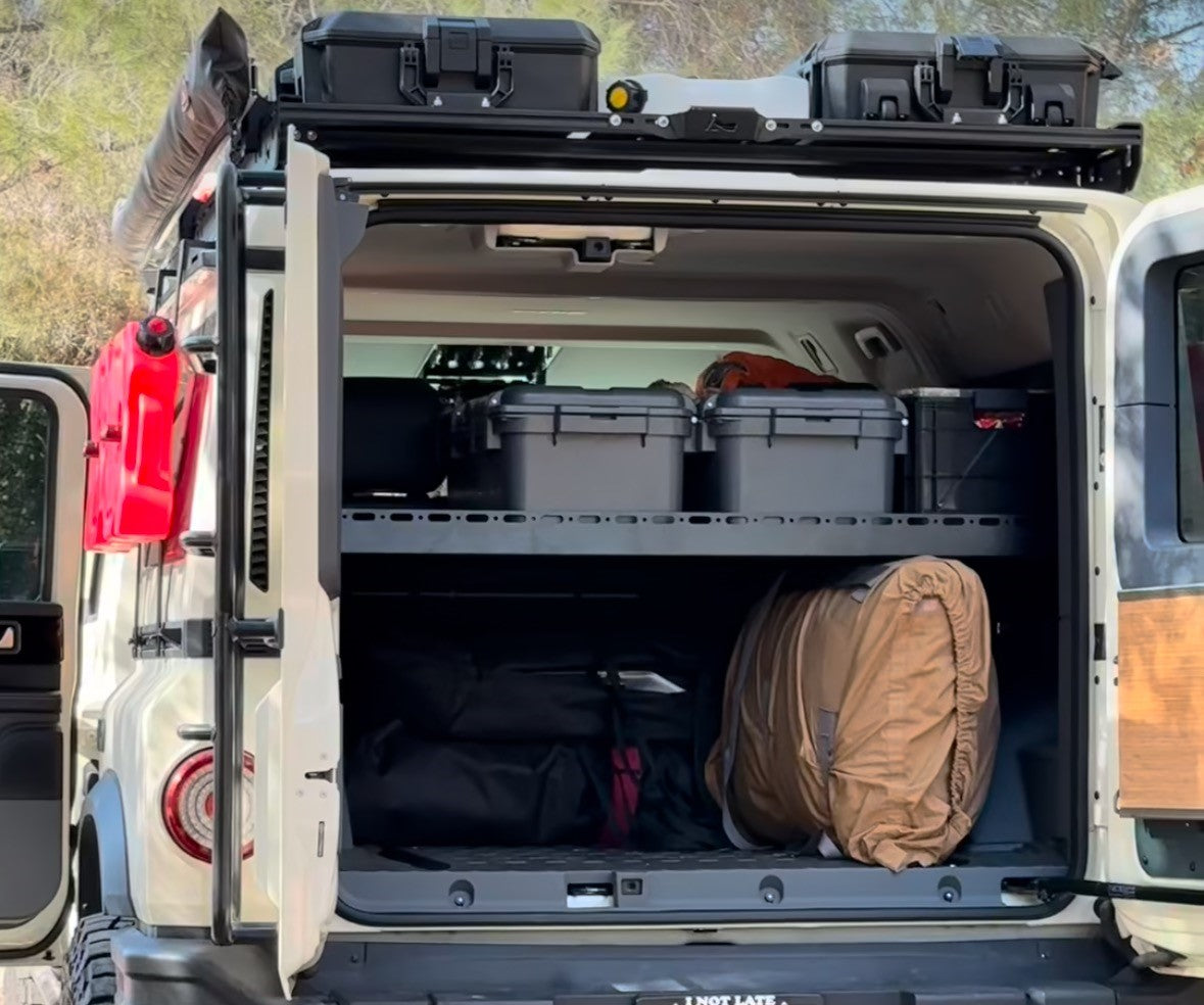 Grenadier with the rear door open, Mid Deck holding hard cases above packed bags