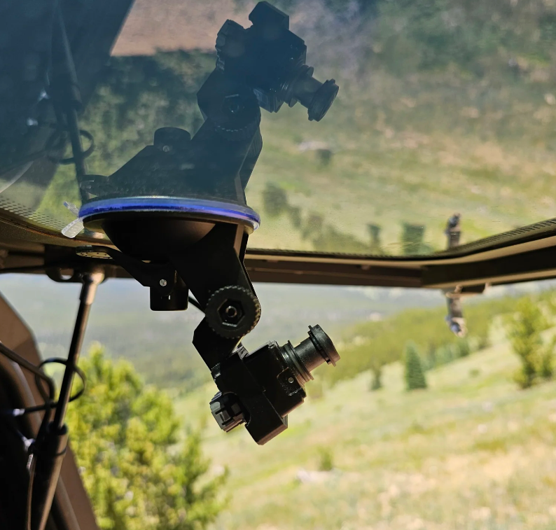 Suction cup camera mount angled on topper glass with a mountain view behind