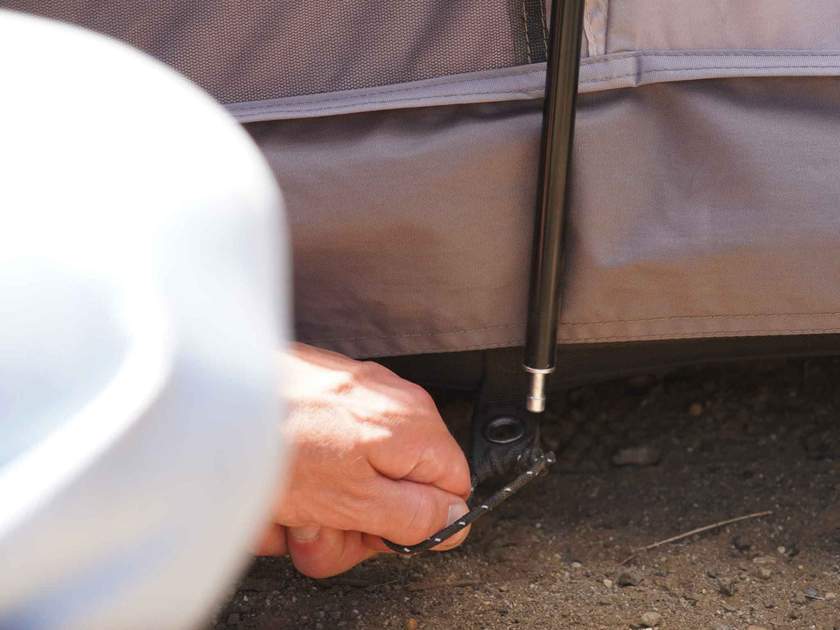 C6 Rev Tent (Element) – hand securing a tent pole at the base