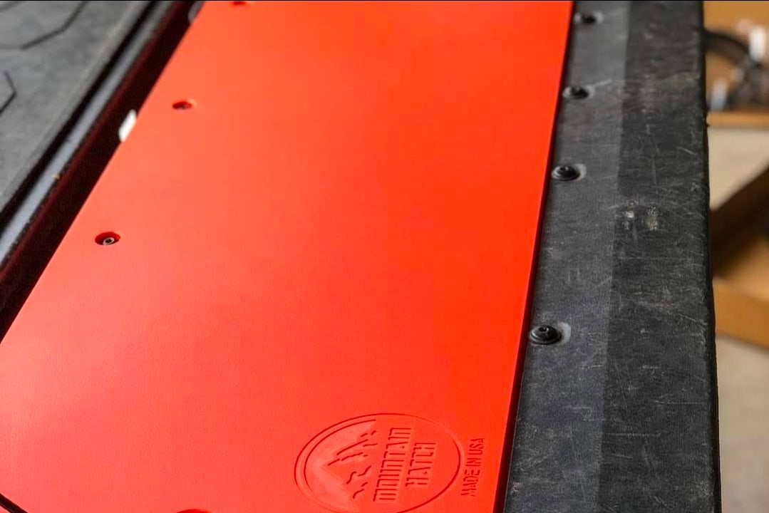 Edge detail of an orange Mountain Hatch panel on a Tacoma tailgate showing 1/2-inch HDPE thickness