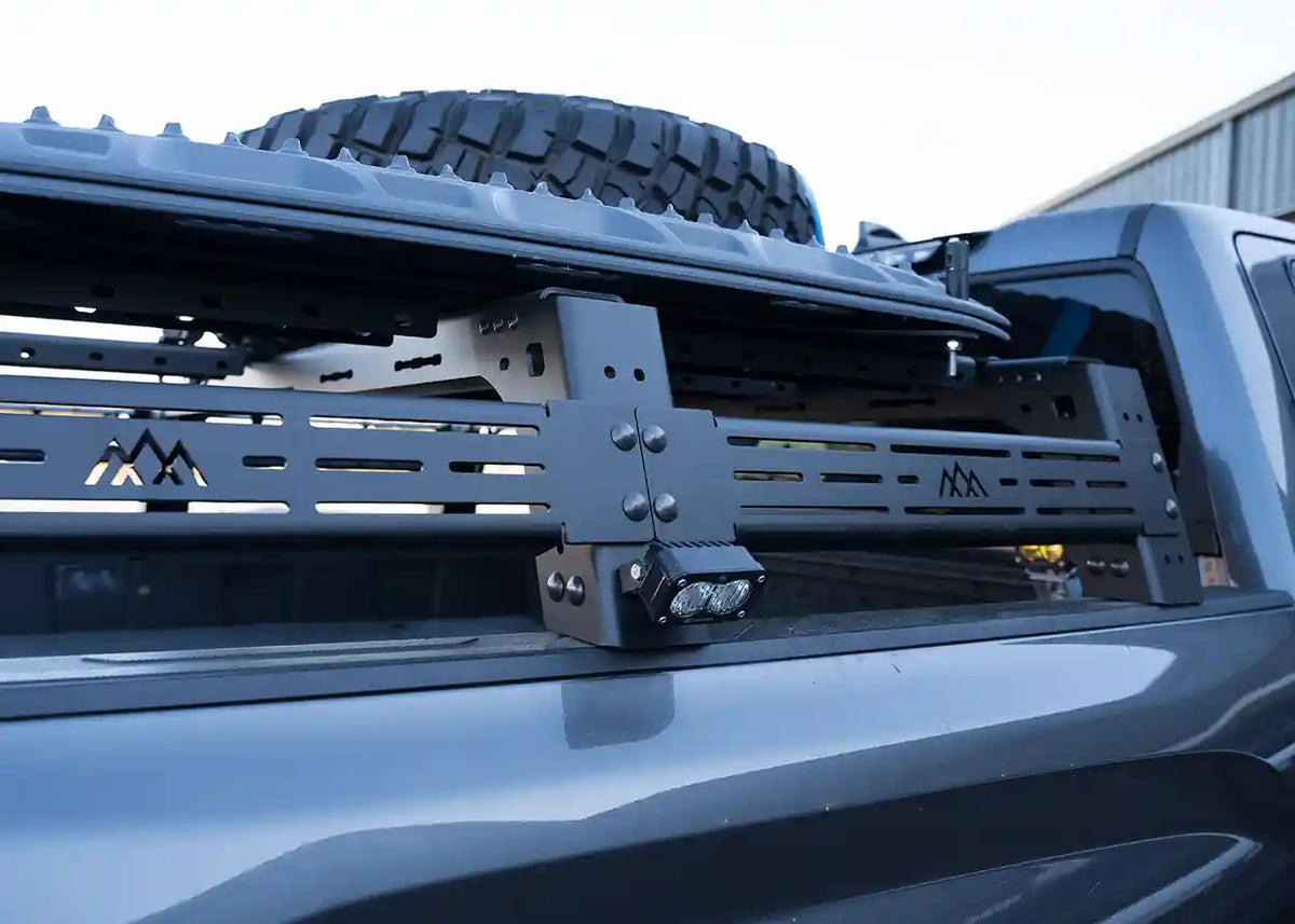 Toyota Tundra Mid Height bed rack, close-up of the cross-brace joint with a spare tire and auxiliary light mounted