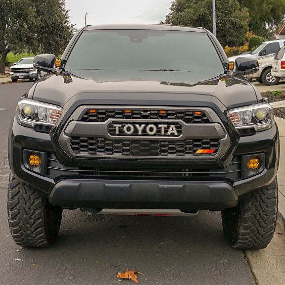 Front view of black Tacoma TRD with amber ditch lights