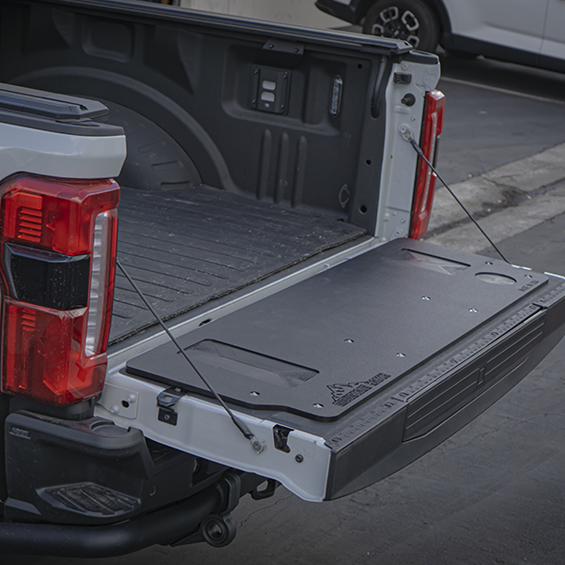 Mountain Hatch tailgate table installed on a white 2023+ Ford Super Duty tailgate, recessed tray and drink holders visible