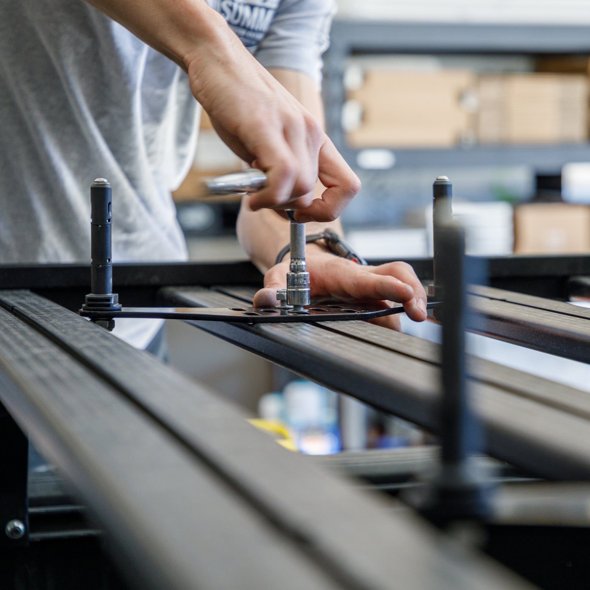Overland Kitted Flat Roof Rack Mount For MAXTRAX - showing a person installing the mount on a Prinsu Rack