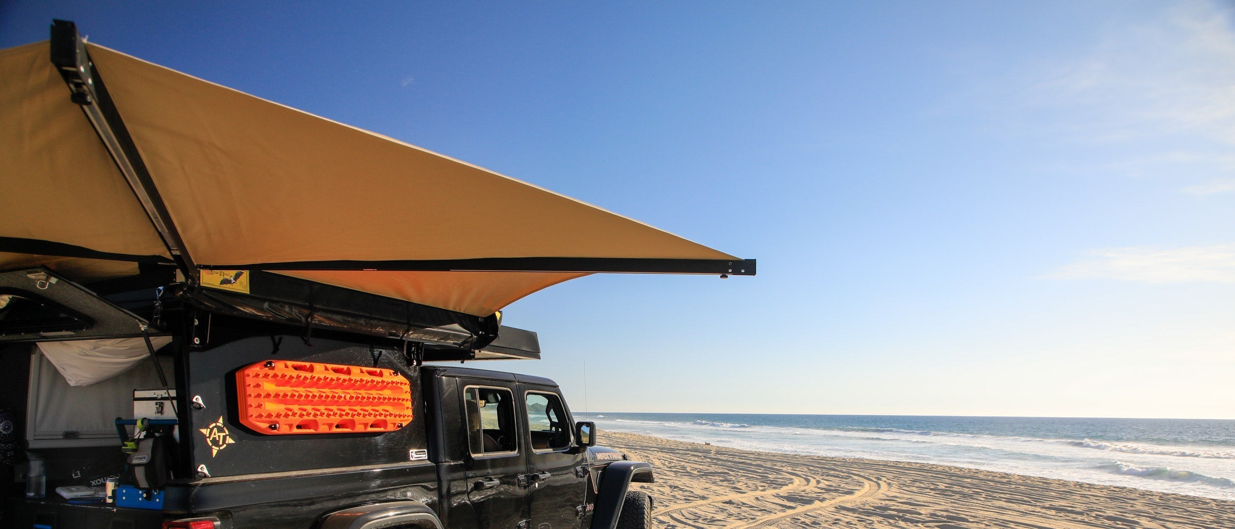 180° vehicle awning extending in a semi-circle from the side of a vehicle, providing shade for camping and overlanding.