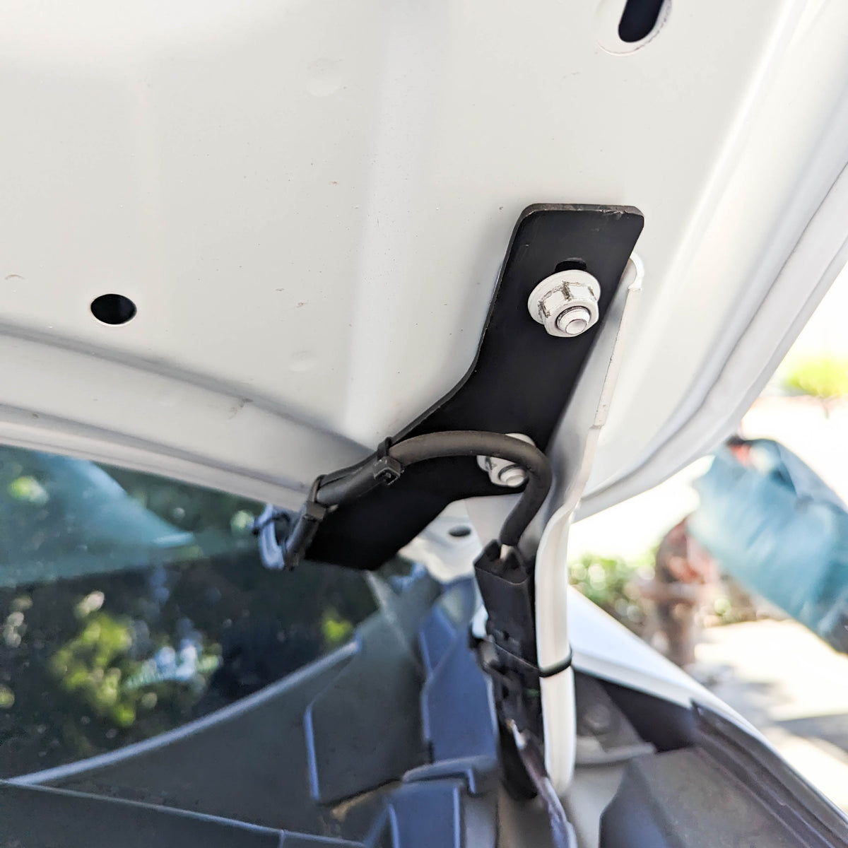 Ditch light bracket bolted under the raised hood near the hinge