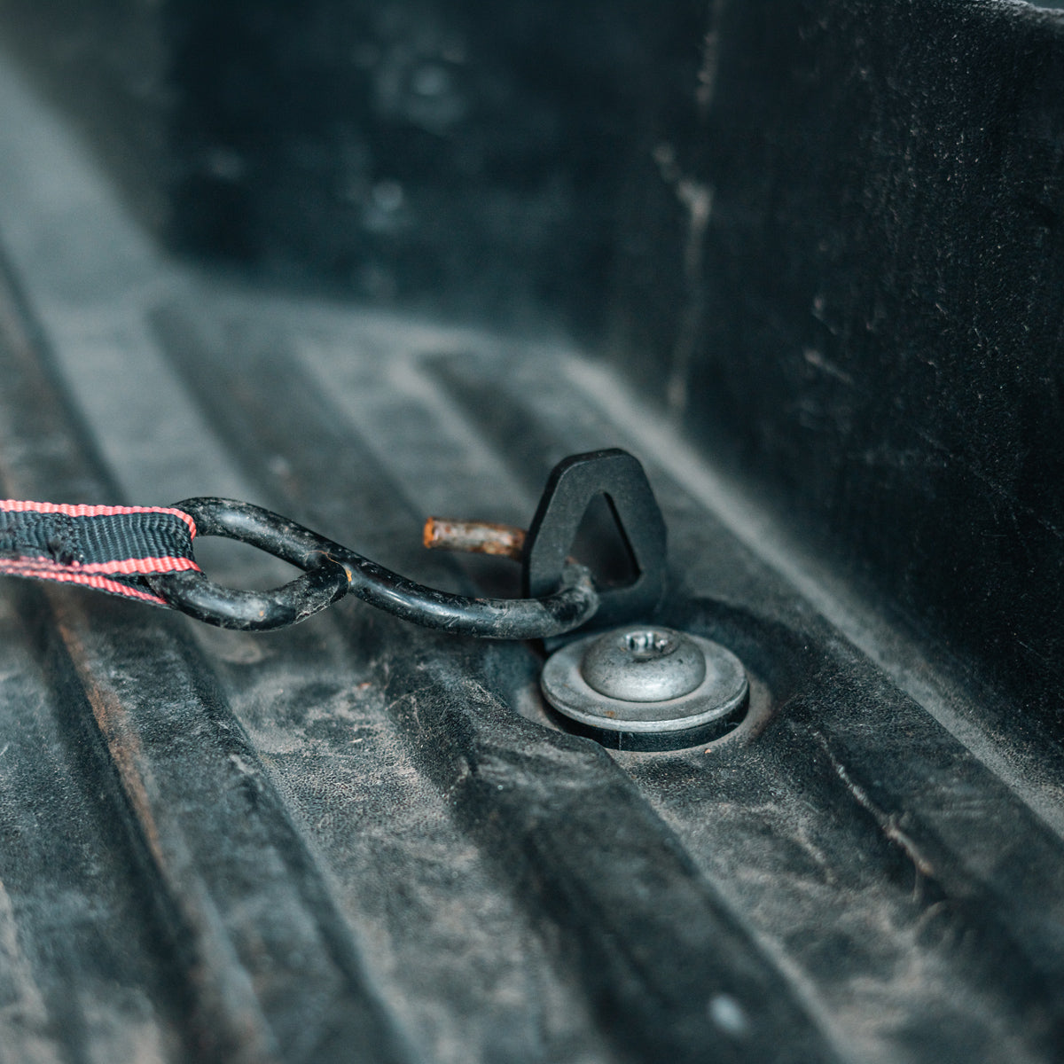 Cali Raised LED bed tie down installed in a truck bed anchor point with a bungee cord hooked through it, wide shot