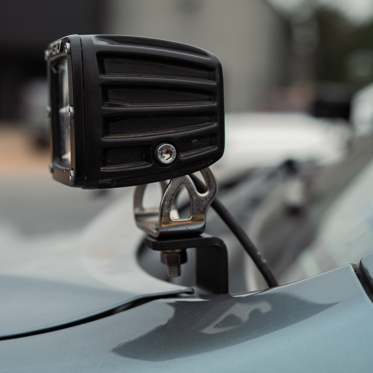 Black LED pod held by a low-profile bracket with the wiring running beneath it