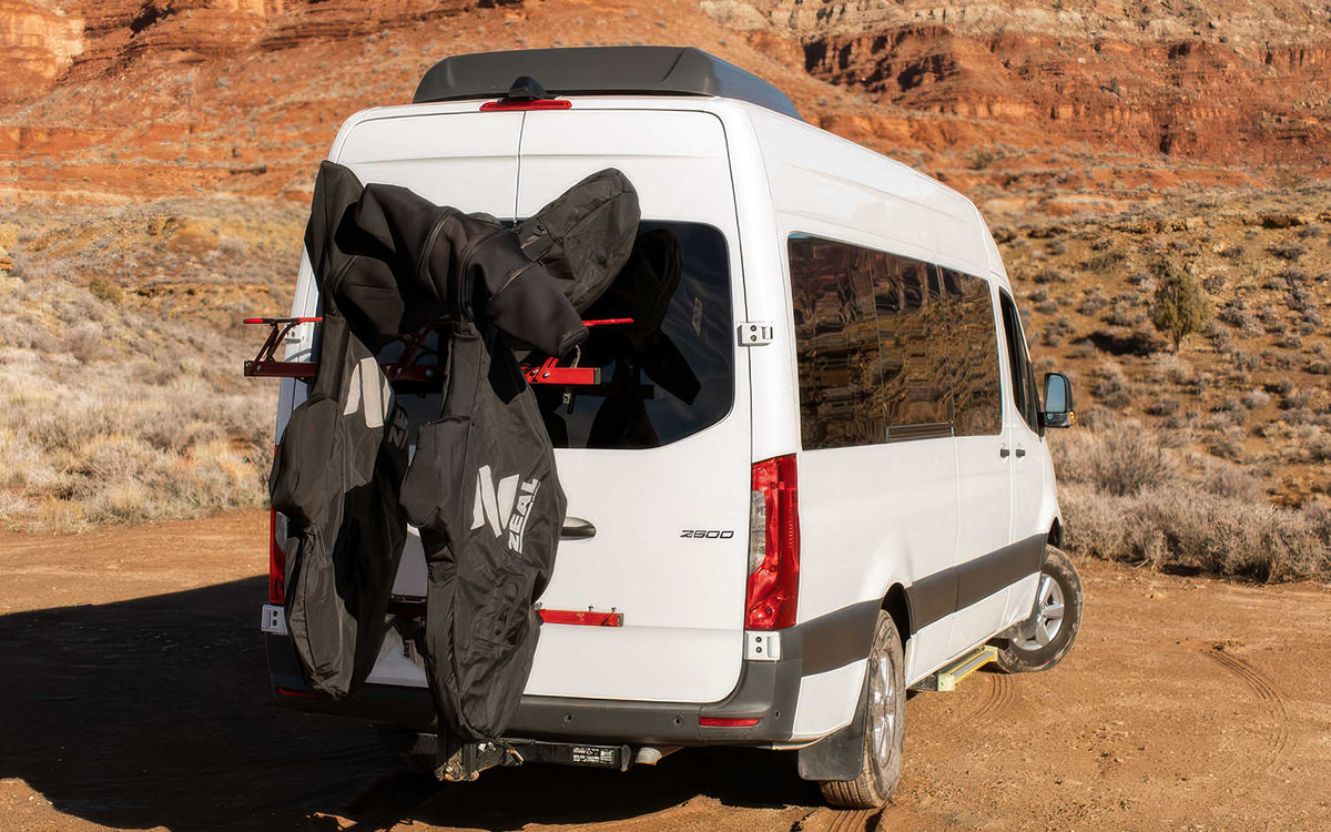 Mountain bikes in ZEAL Pro covers on a hitch-mounted VelociRAX rack on a white Sprinter van