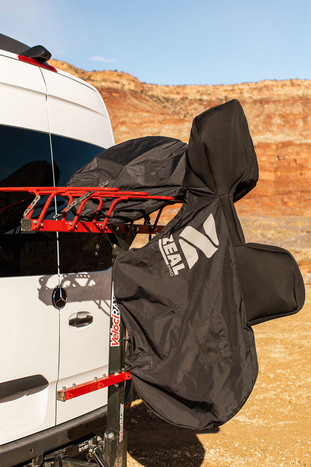Side view of a covered mountain bike hanging from a VelociRAX rack on a white Sprinter van
