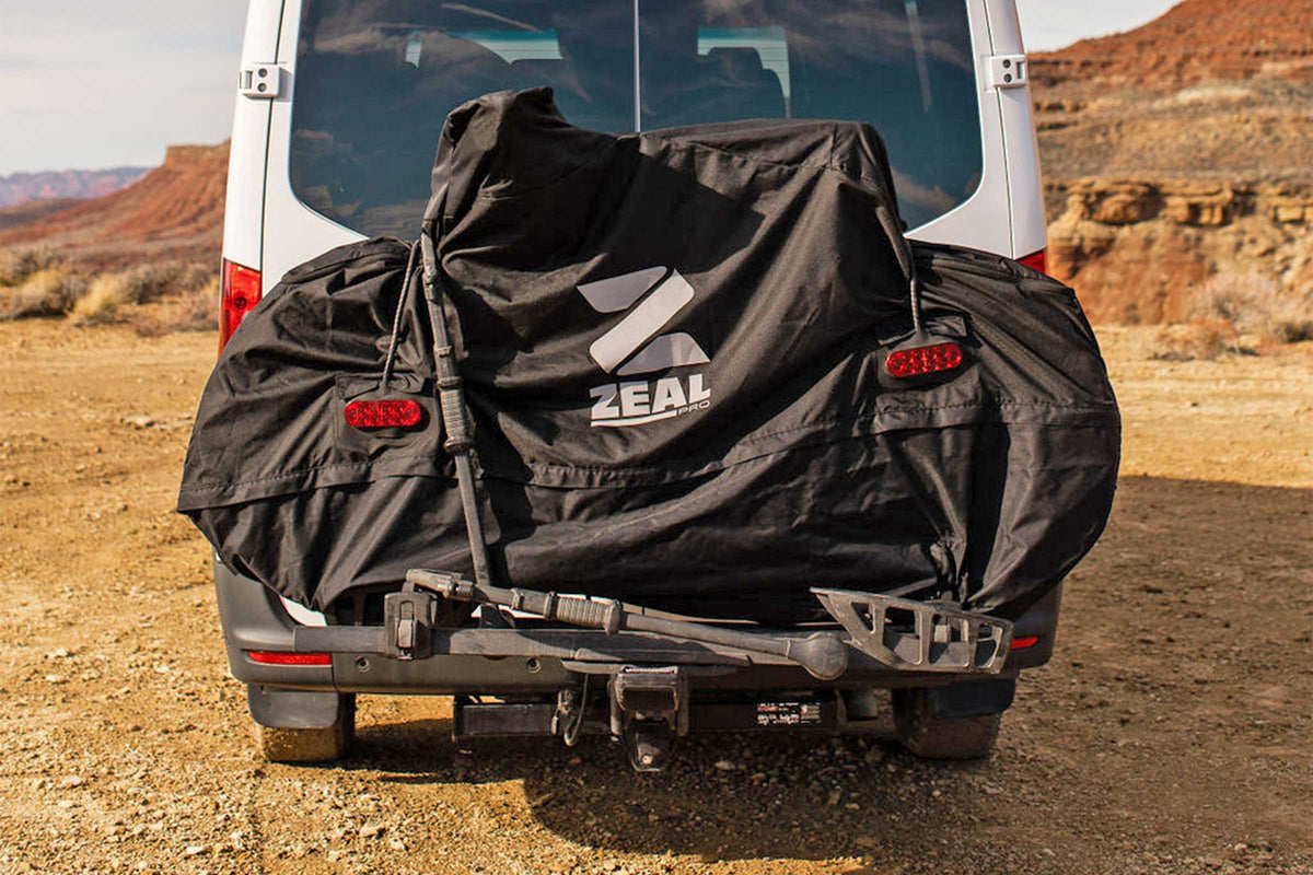 Rear view of the e-bike cover with tail lights lit on a hitch rack behind a Sprinter van in the desert