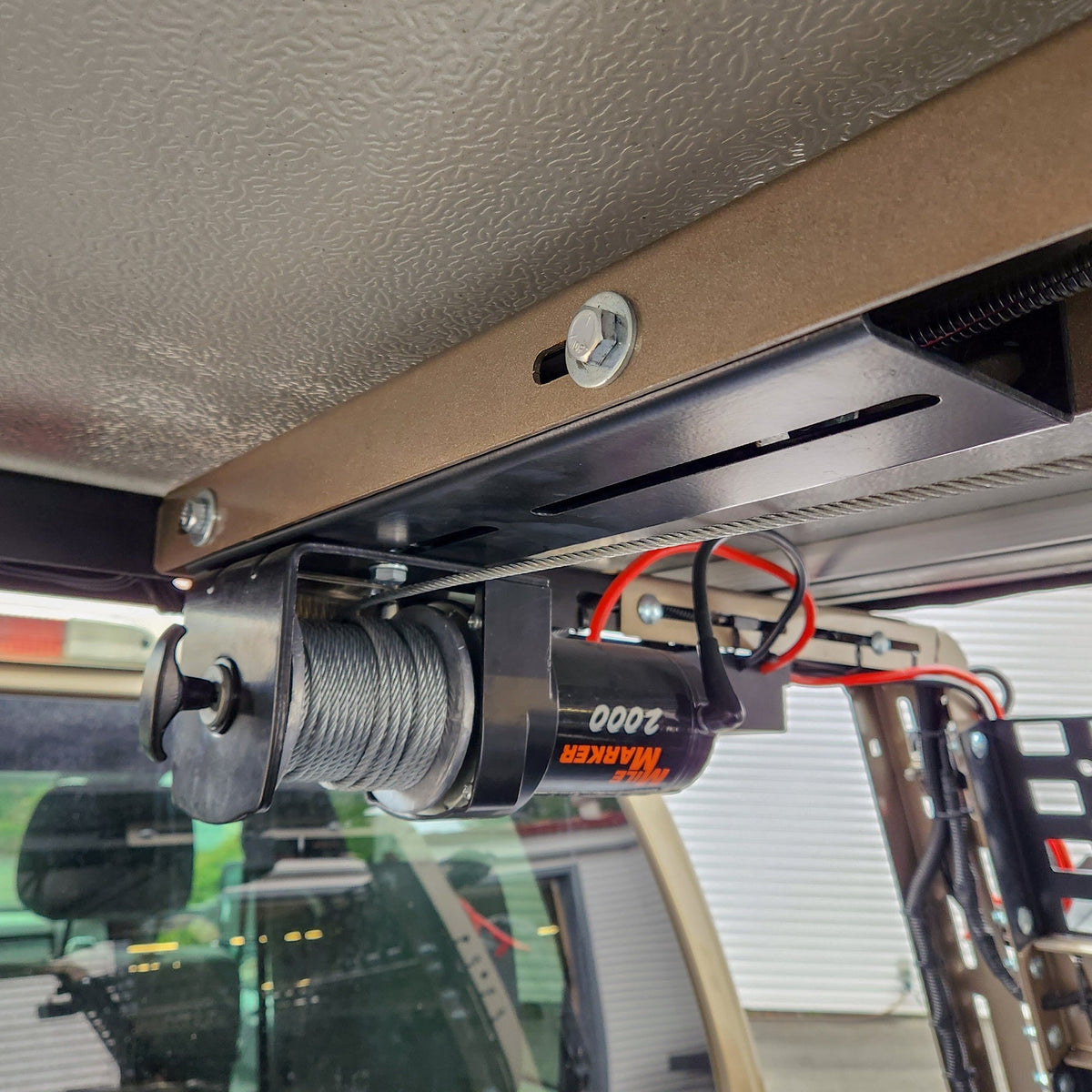 2,000 lb winch hanging from an HMOR ROCK-IT winch mount under the rack