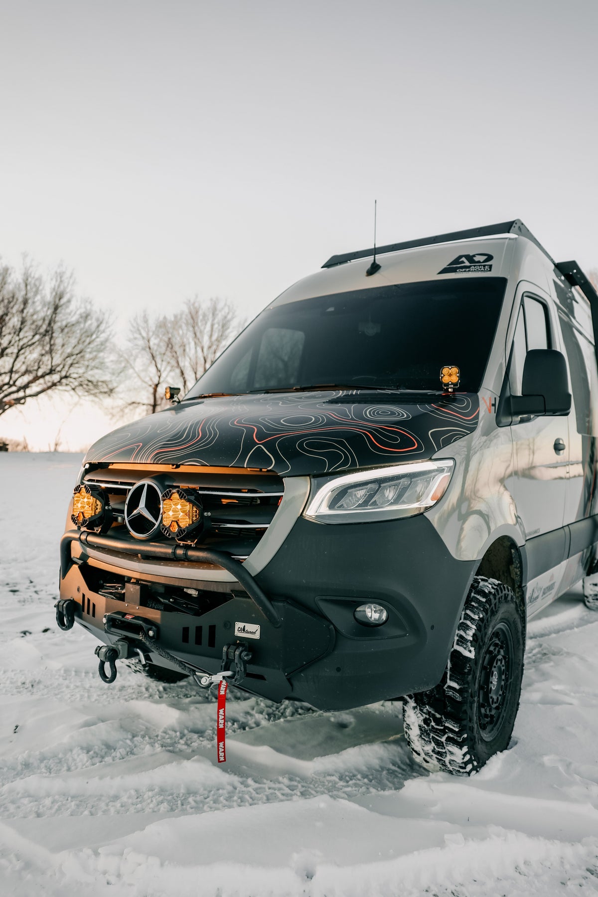 Van parked in snow with amber lights lit at the front