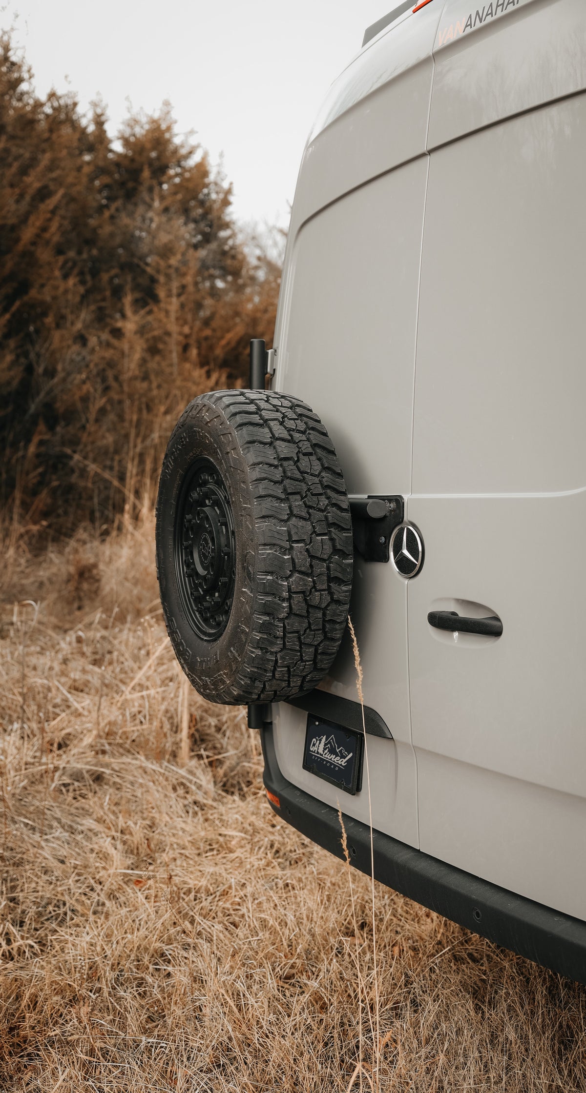 Spare tire carrier on the rear door of a van in a grassy field