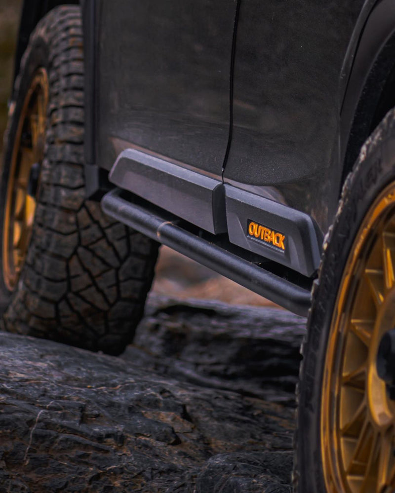 Black rock slider mounted along the lower body of a dark SUV beside a front wheel
