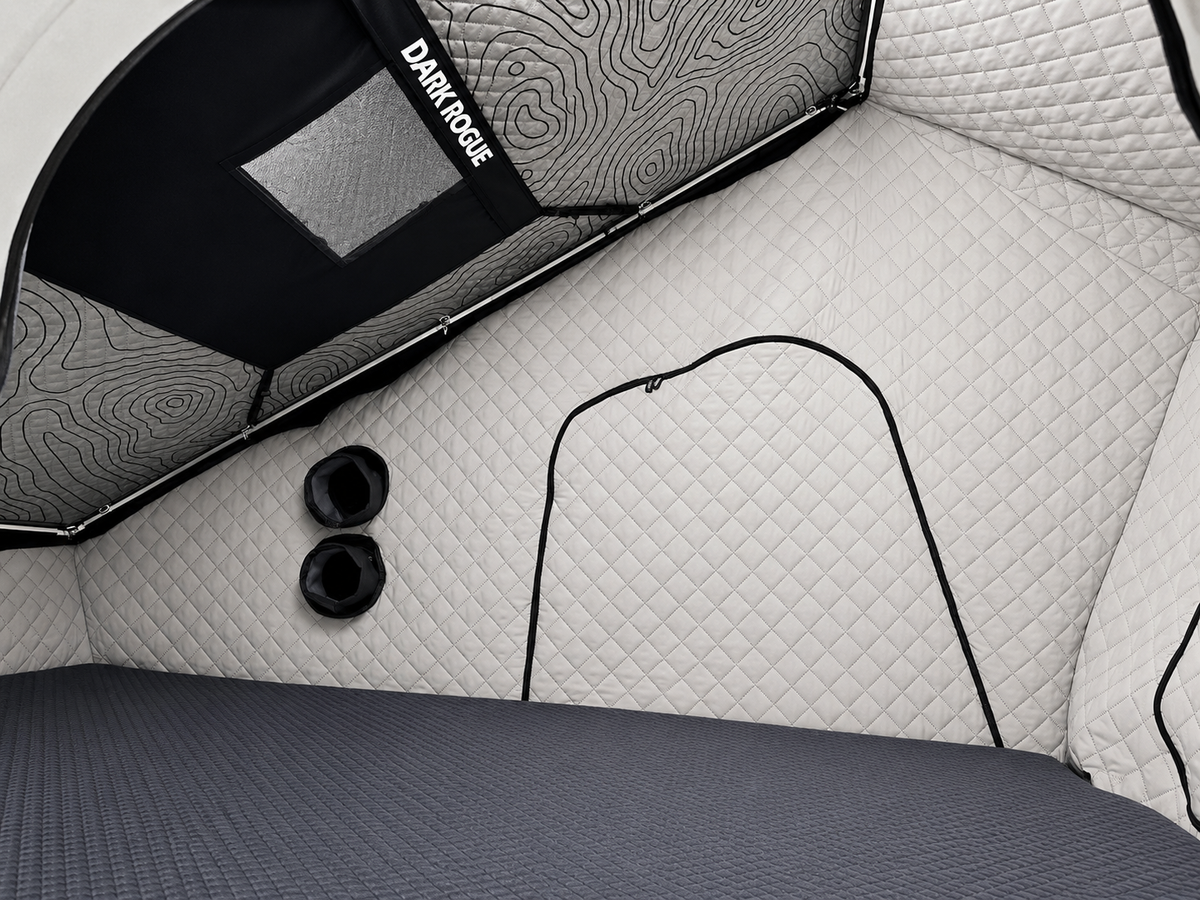 Interior corner of the Dark Rogue tent with quilted walls, a zippered opening and two round port openings