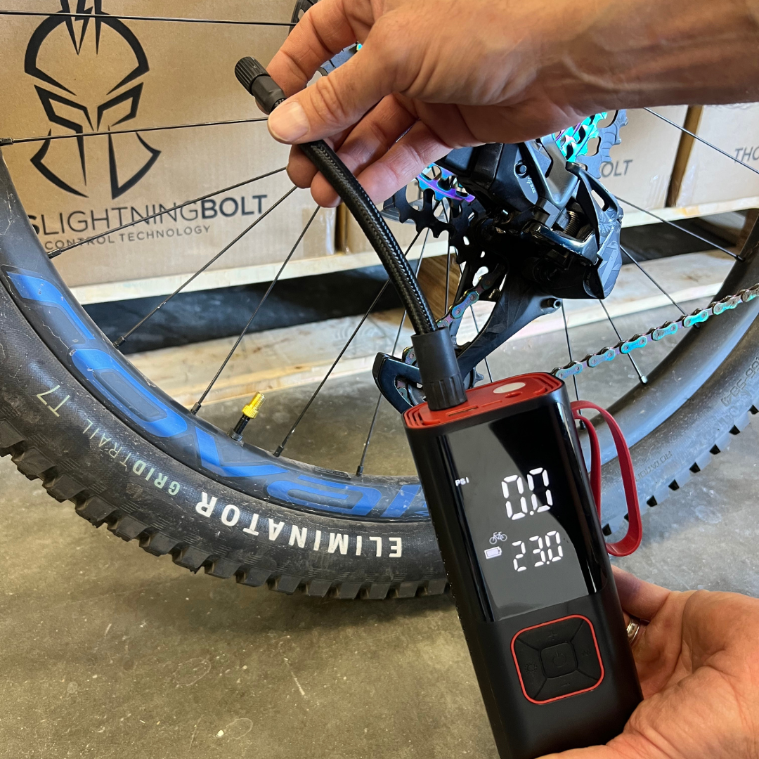 Lifestyle photo of the AirSpark compressor inflating a mountain bike tire, digital display reading current and target PSI