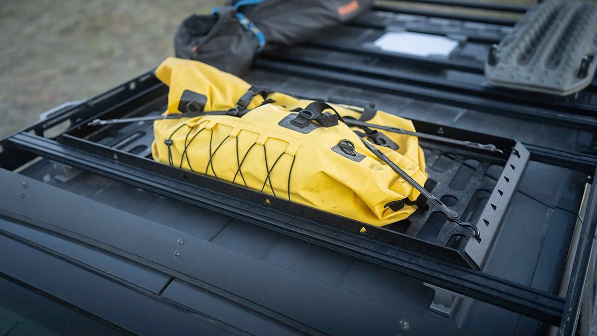Yellow dry bag strapped into the Roof Rack Storage Basket mounted on a vehicle roof rack