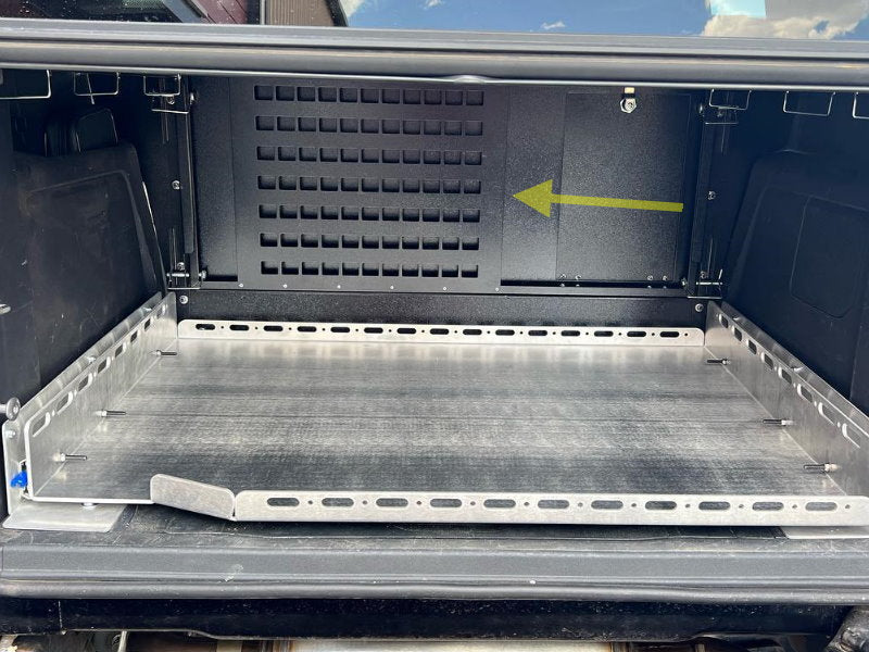 Arrow pointing to the forward wall MOLLE panel above a raw aluminum slide tray