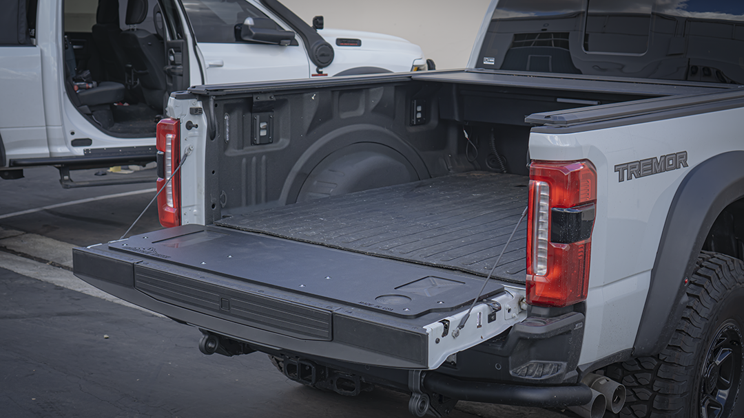 Wide rear view of a 2023+ Ford Super Duty with the Mountain Hatch panel on the lowered tailgate