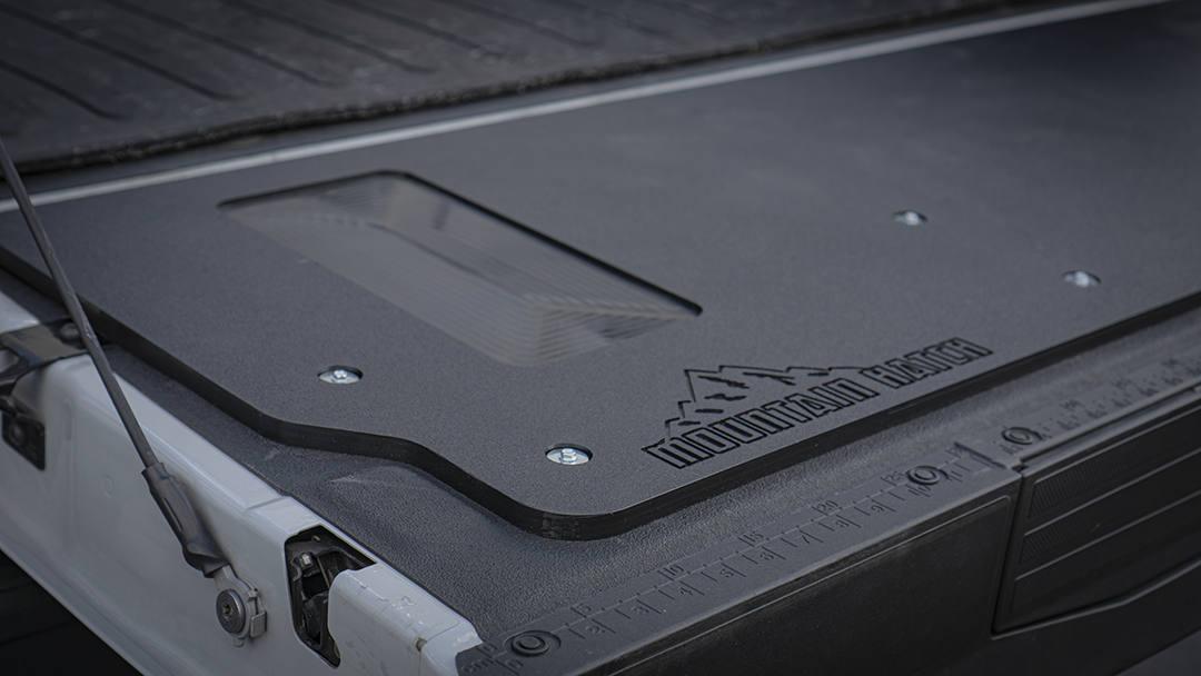 Mountain Hatch logo stamped into the textured black HDPE surface on a 2023+ Super Duty tailgate