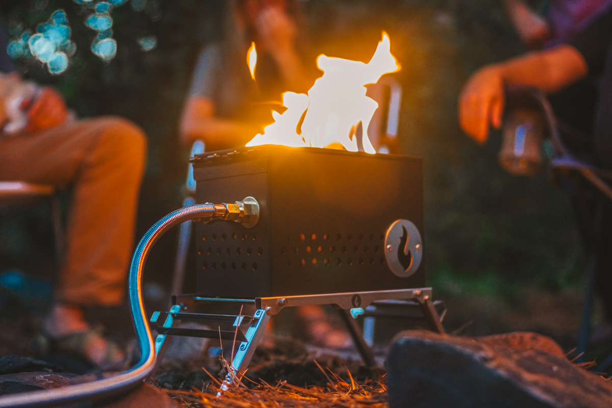 Close-up of a firebox lit with visible flame, with people seated around it