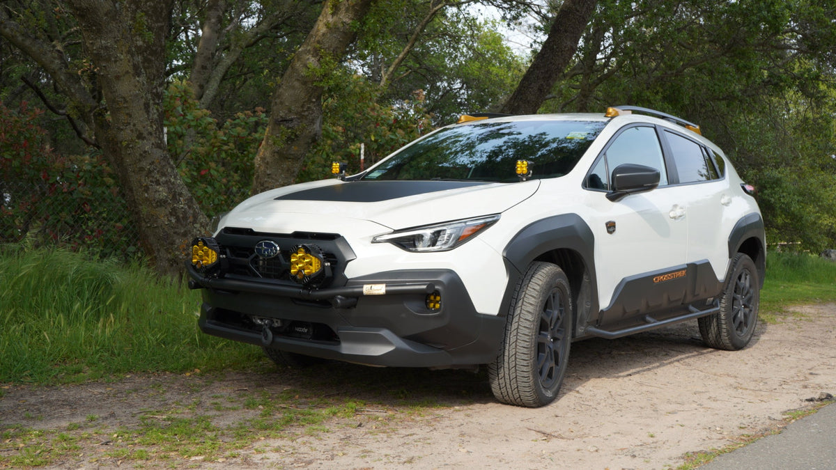 White Subaru SUV with amber lights parked on grass
