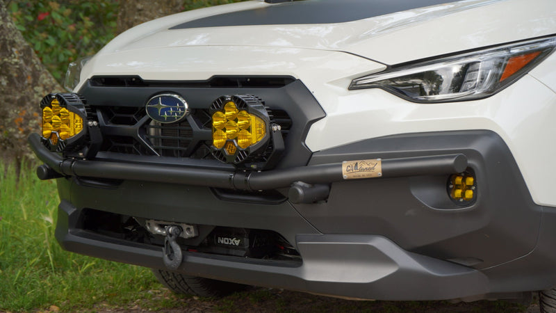 Front of a white Subaru SUV with a black brush bar and amber light pods at the grille