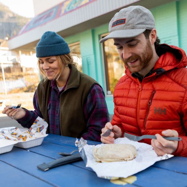 Two people at an outdoor table eating with the UCO ECO utensils
