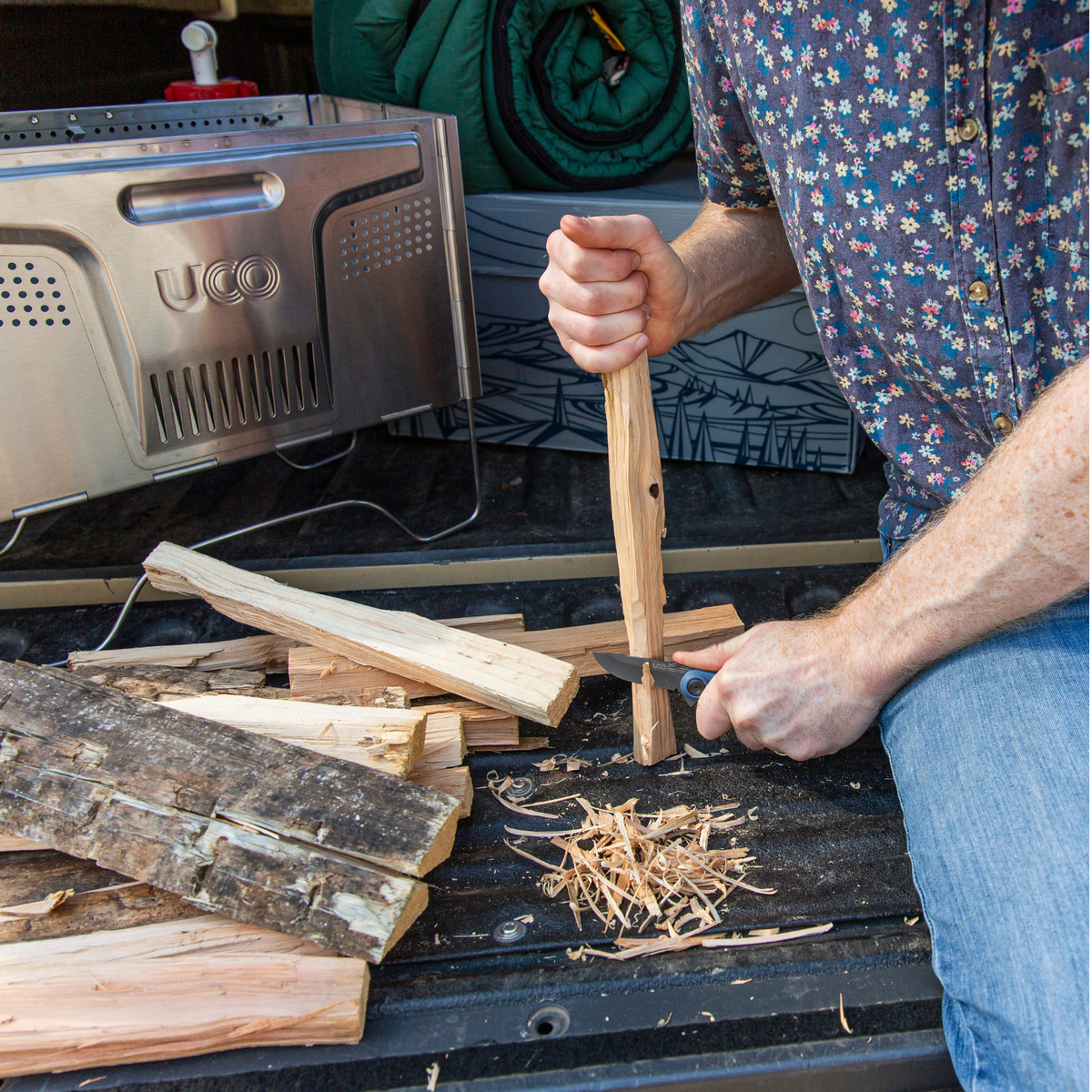 Close-up of a hand splitting kindling with a hatchet for a campfire