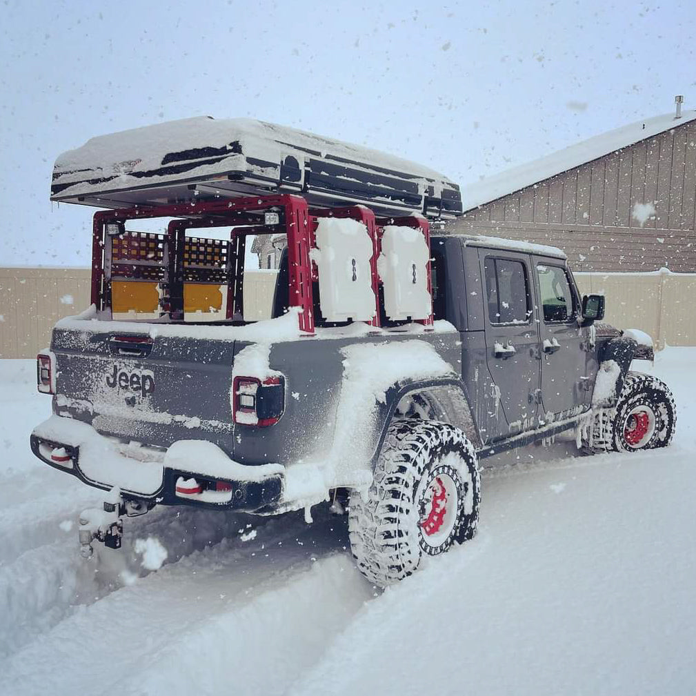 Gladiator with ROCK-IT rack and water cans driving through deep snow
