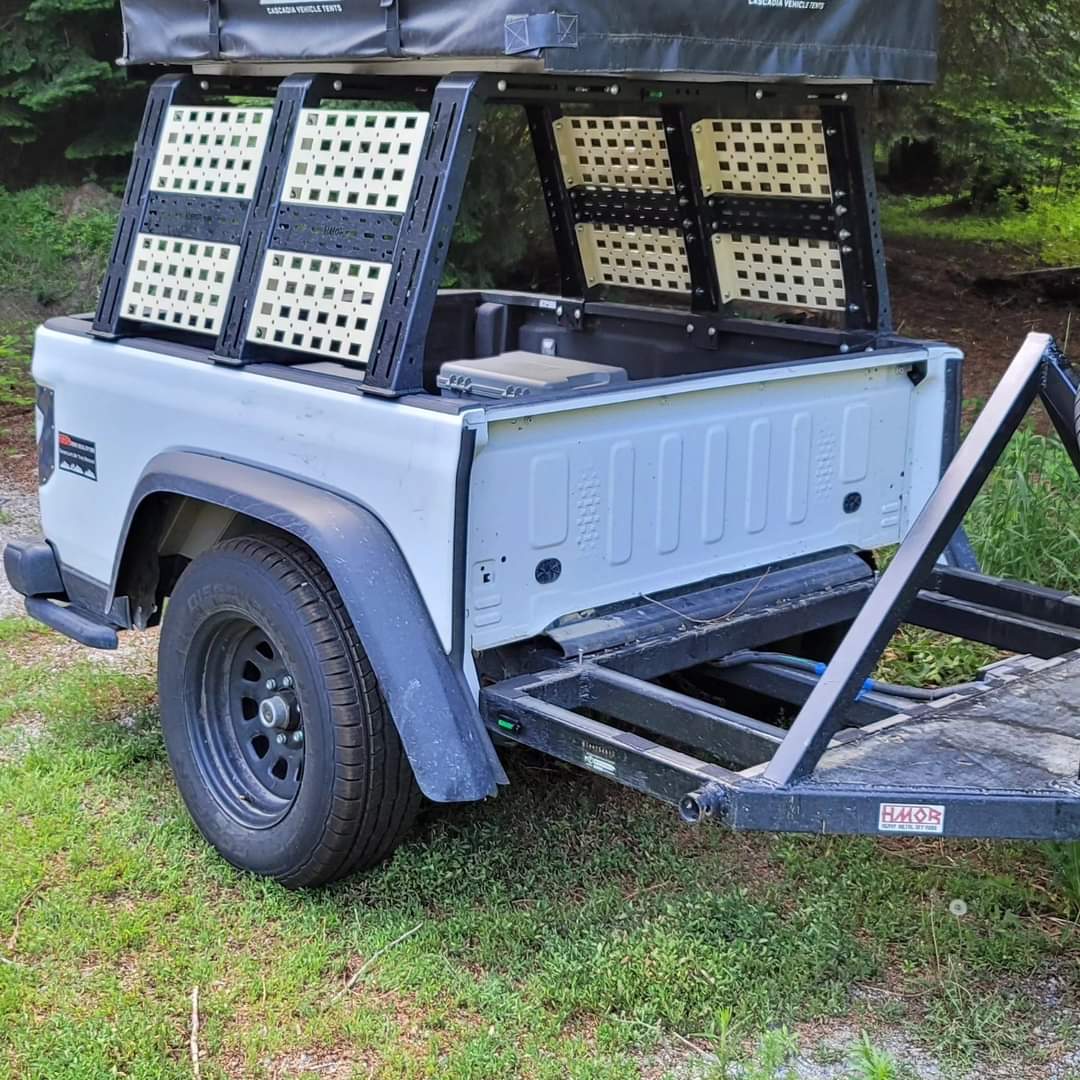 ROCK-IT rack with tan MOLLE panels on a white Gladiator bed on a trailer