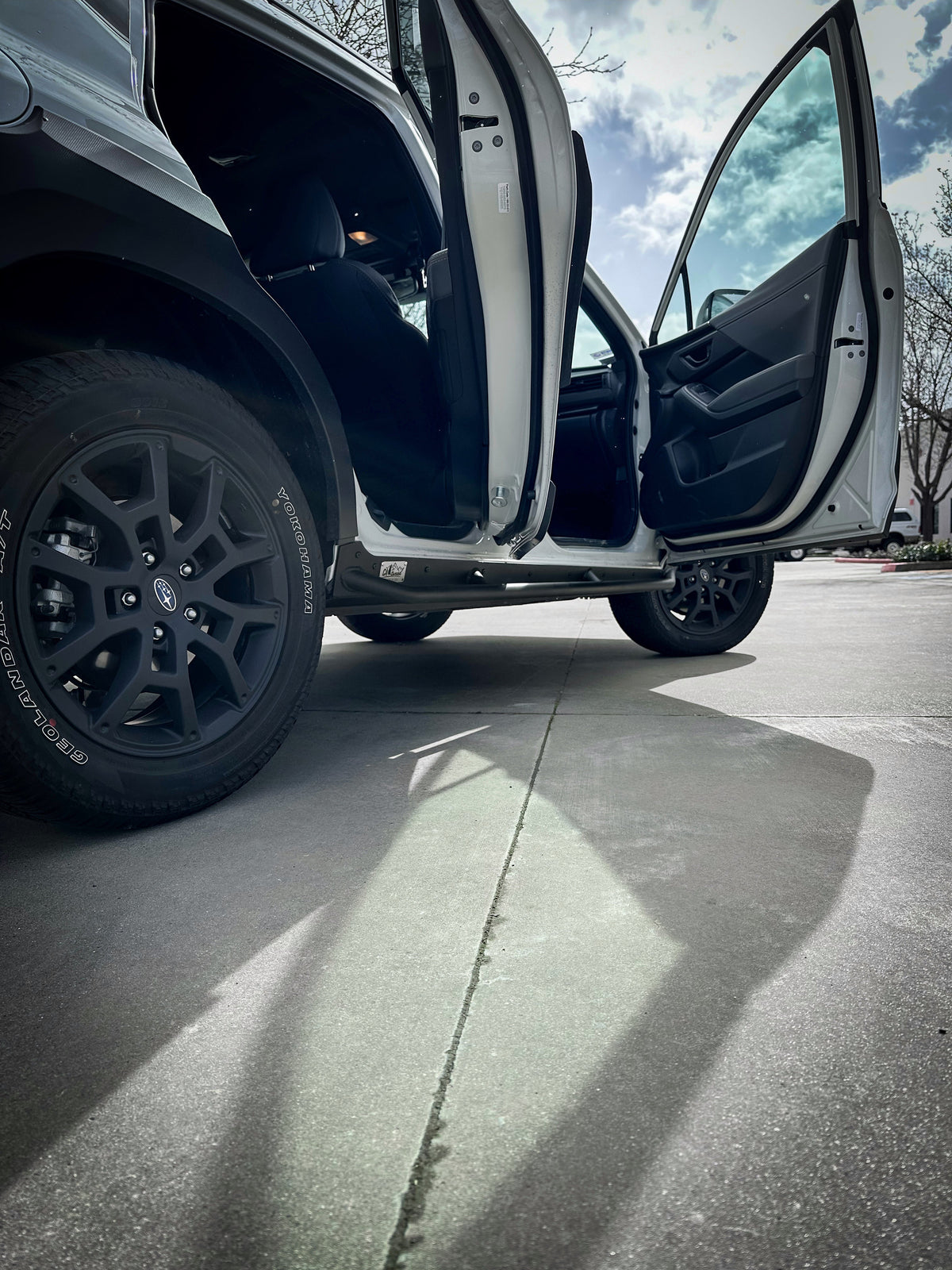 Open front door of a white SUV above the rock slider
